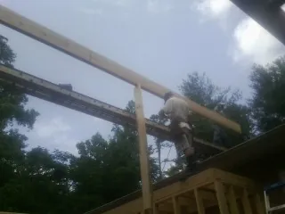 Carpenter setting a ridge beam over a new addition frame — Ice Dam Removal by Roofing Brothers in Spring Glen