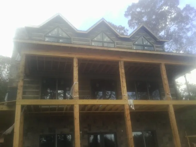 Dormers and porch framing on a large log home under construction — Roof Coating work by our crew in Spring Glen