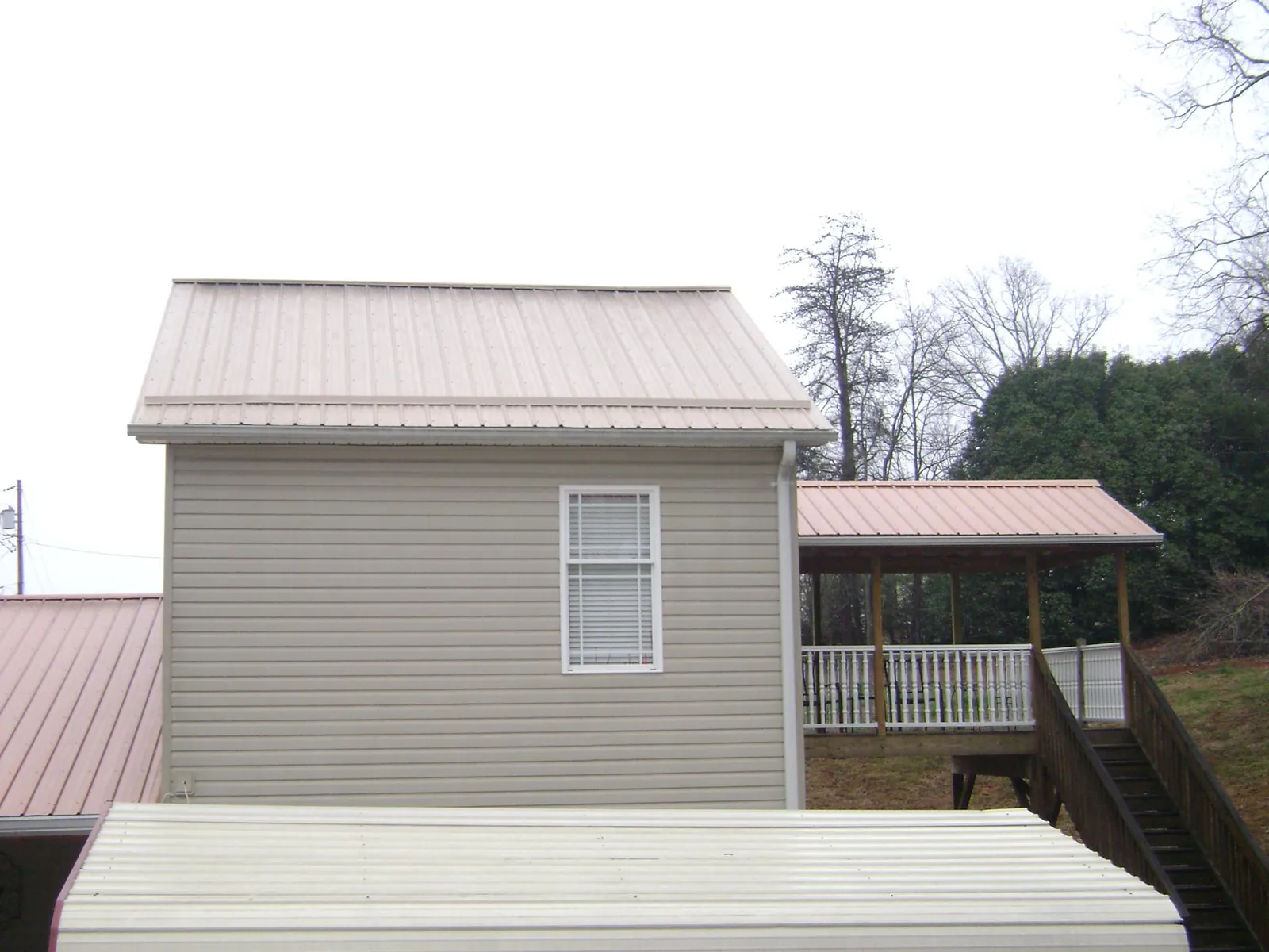 Tan metal roofs on a two story addition and attached porch, from a Roof Replacement job in Spring Glen
