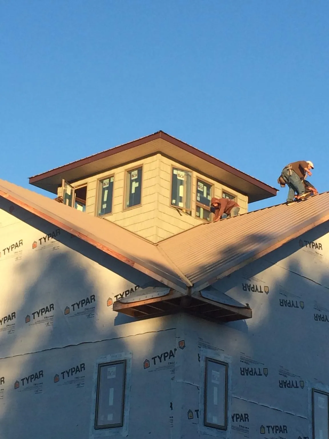 Roofers working around a rooftop cupola on a new metal roof at sunset — Roof Waterproofing in Spring Glen by Roofing Brothers